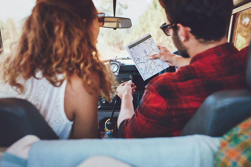 Mężczyzna i kobieta w samochodzie szukają na papierowej mapie trasy dojazdu